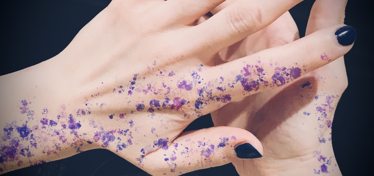 Closeup of two hands with purple paint splatters on them