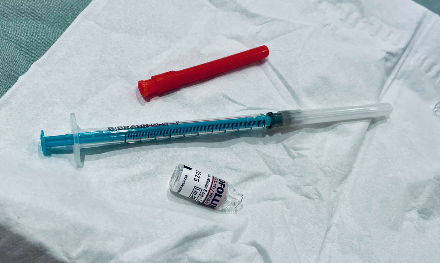 Used injection needle and an empty vial of neofollin