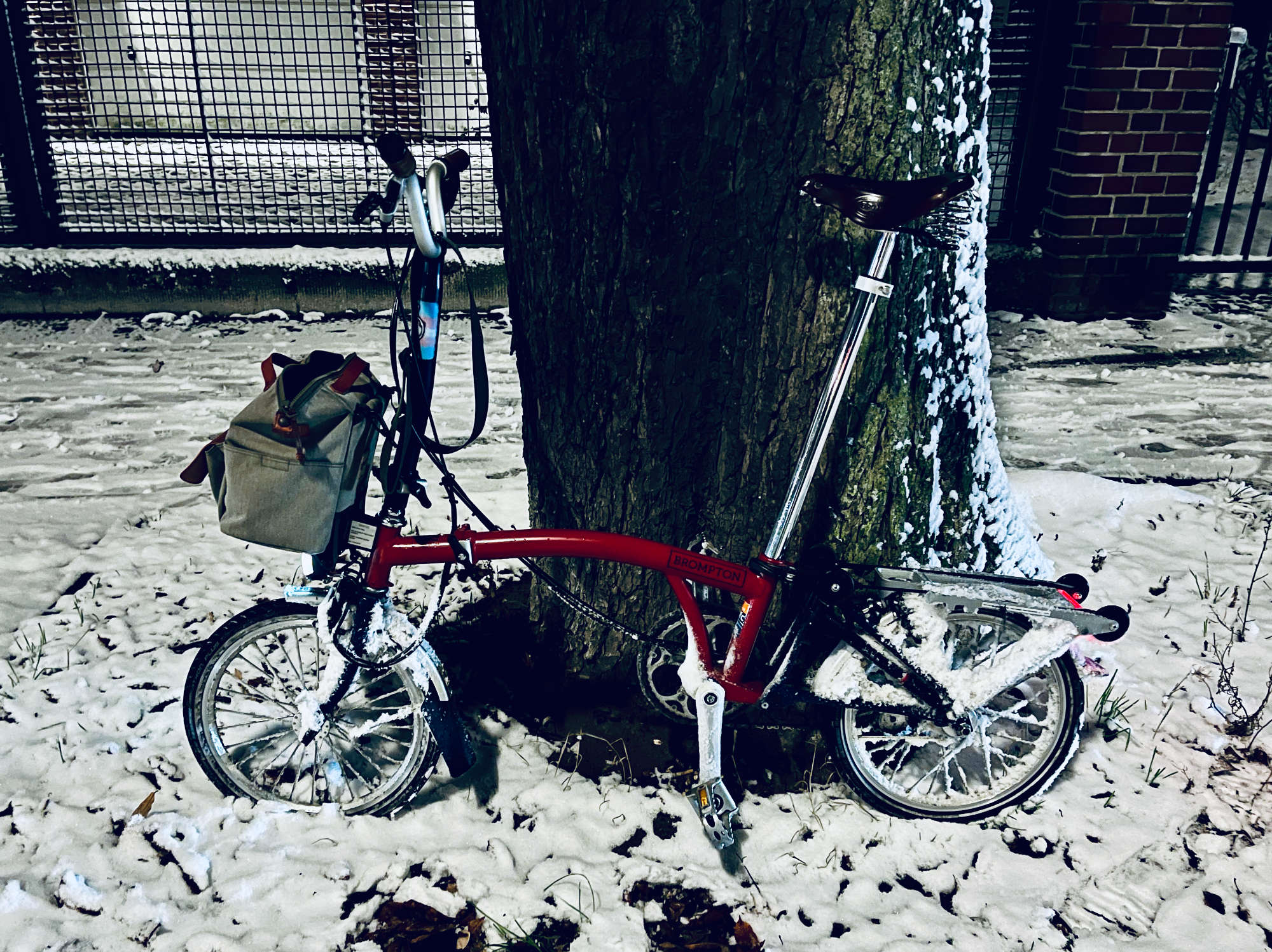 Brompton folding bike covered in snow around the wheels at night