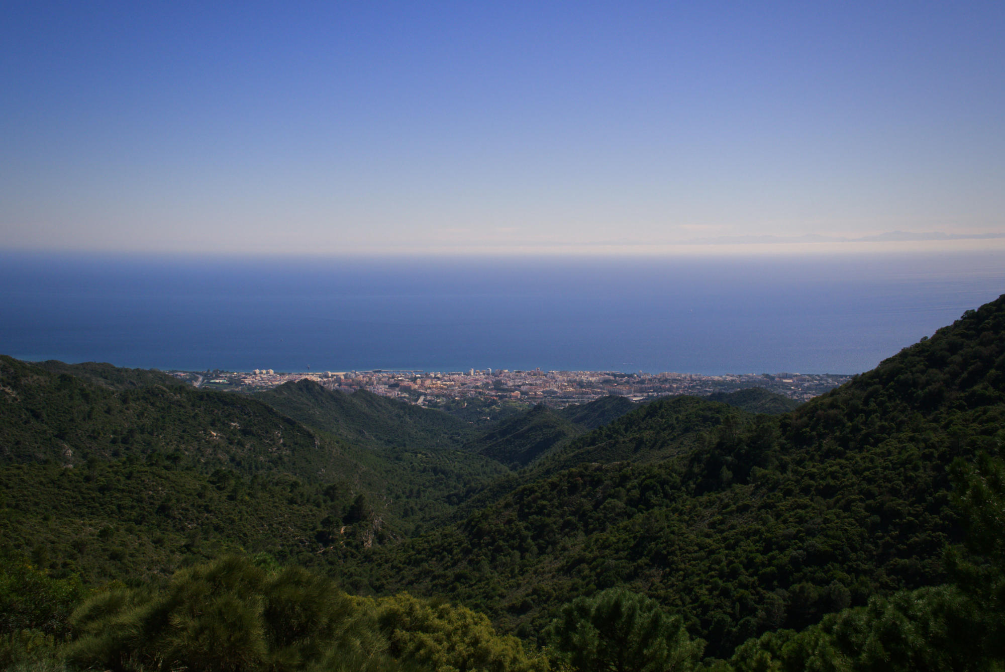 landscape view of forest covered mountains and hills stretching to the far-off ocean in the background