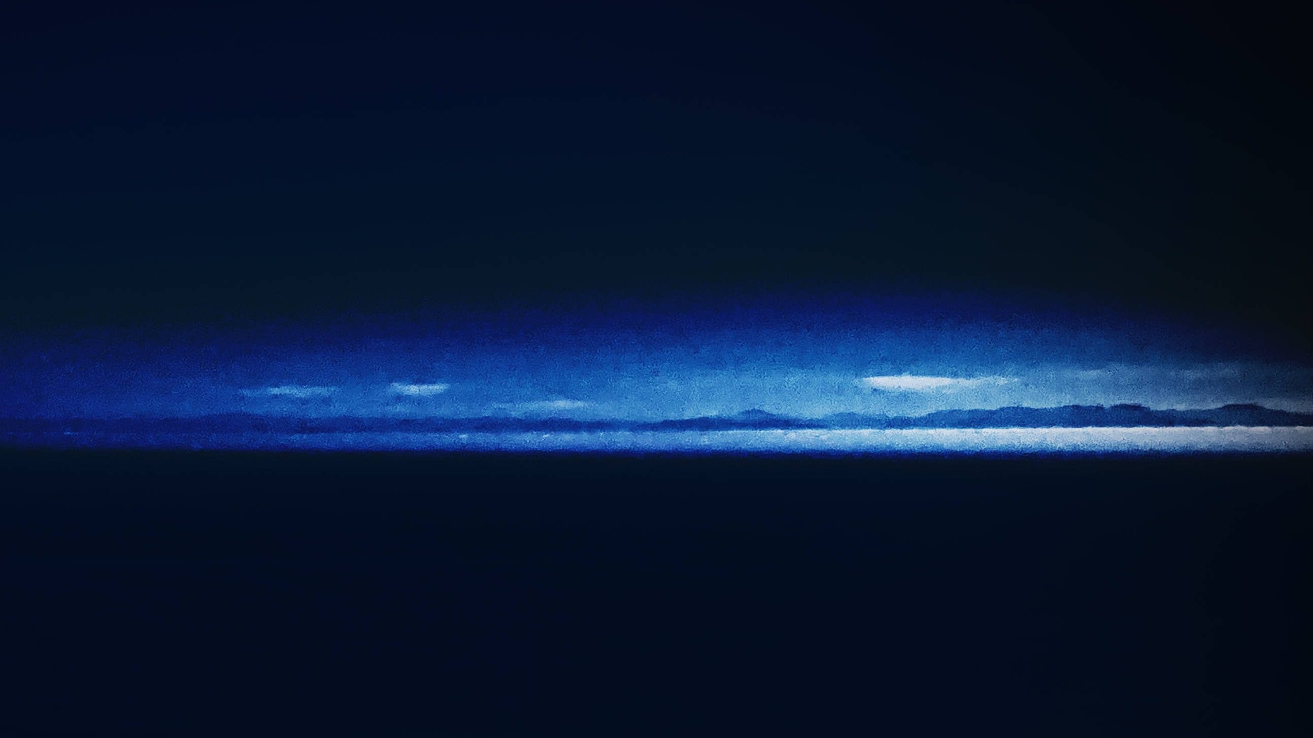 stylized dark photo of the ocean with a chain of mountains at the horizon