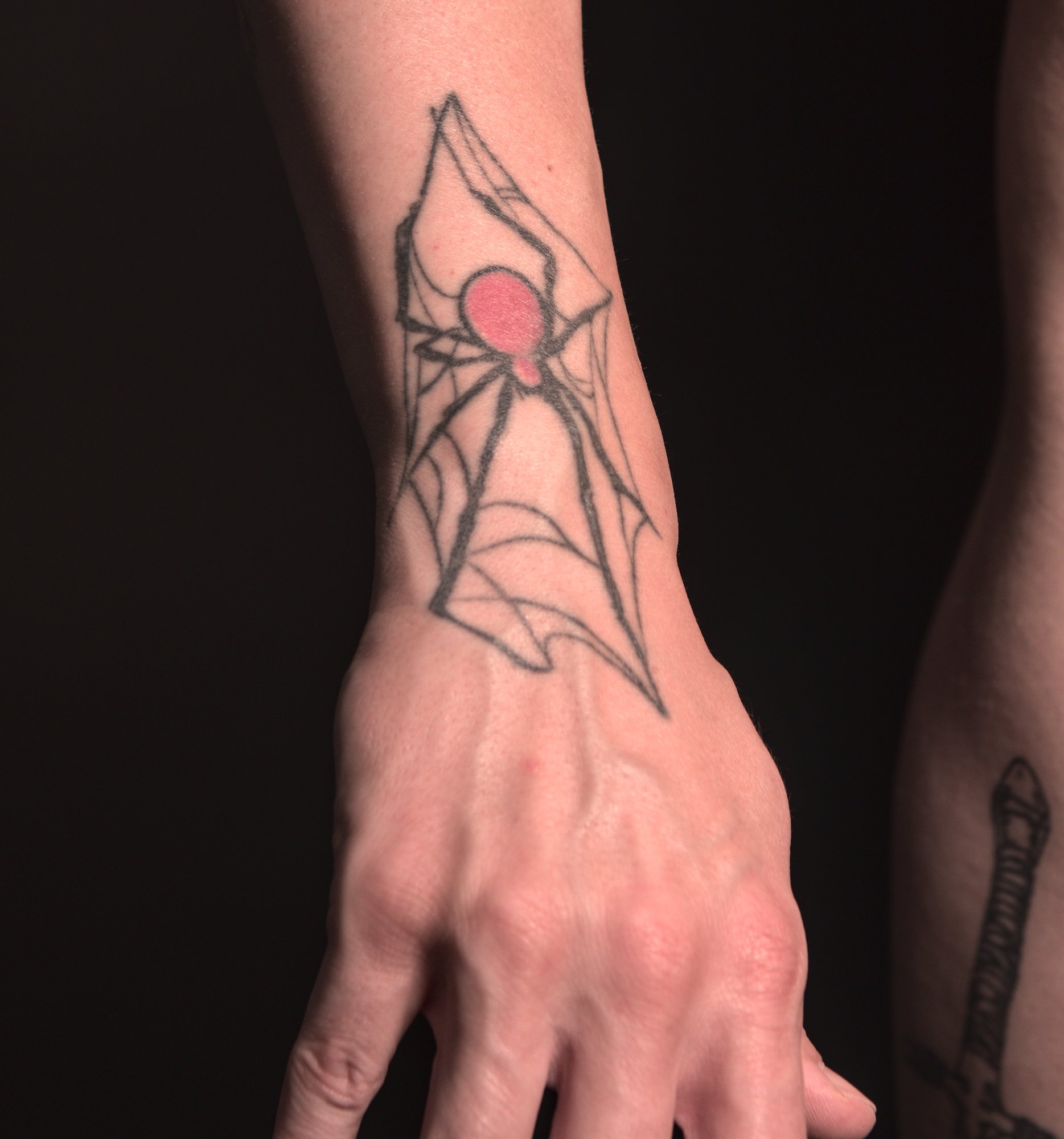 tattoo of a spider on the wrist and back of the right hand